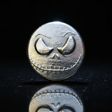 hand poured polished zinc round with a skull design on a light gray background