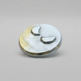 hand poured polished zinc round with a zinc skull design on a light gray background