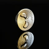 hand poured polished zinc round with a face design on a white background