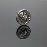 Silver coin with a face on a light gray background