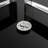 Silver coin with a face on a light gray background