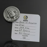Silver coin with a label on a white surface