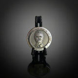 polished Zinc round with a portrait etched onto the front, sitting in a black display stand on a white background